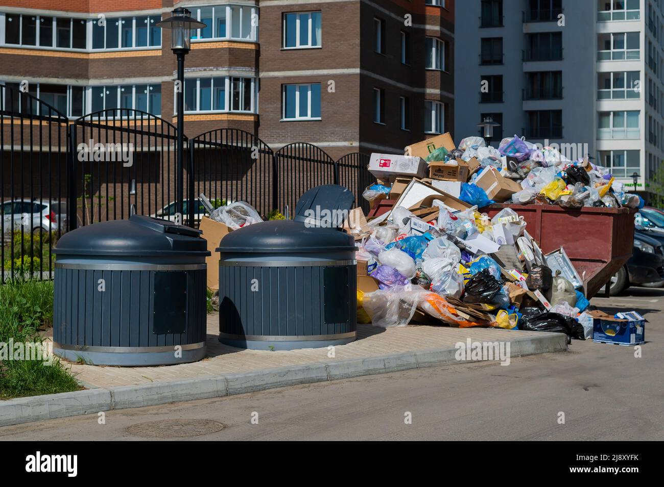 https://c8.alamy.com/comp/2J8XYFK/crowded-garbage-cans-in-the-courtyard-of-a-residential-apartment-building-garbage-sorting-containers-trash-is-scattered-on-the-sidewalk-2J8XYFK.jpg