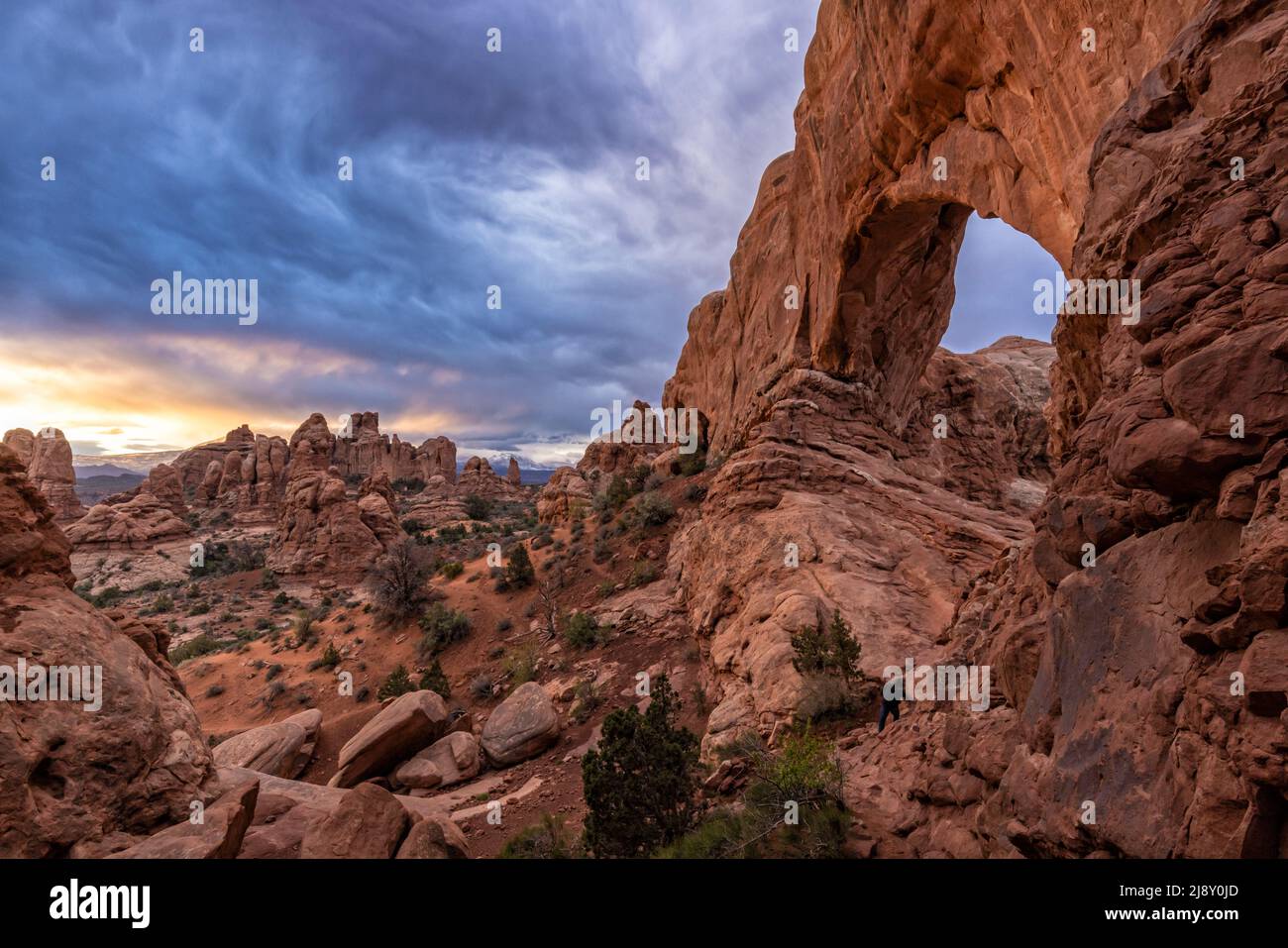 Ominous swirling clouds above the North Window Arch at sunrise in Arches National Park in Moab, Utah. Stock Photo