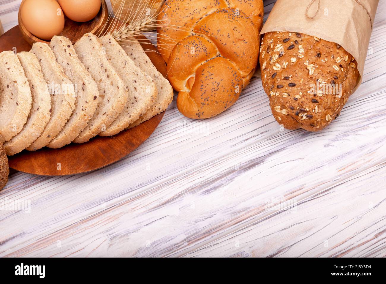 Wholegrain bread put on kitchen cutting board on wooden background. Stock Photo
