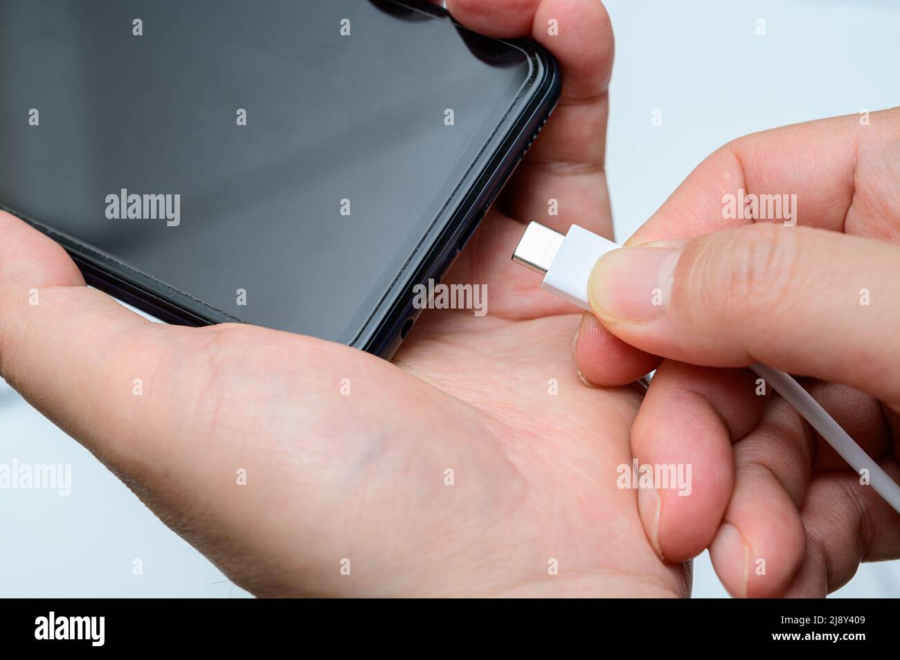 Man's hand connecting type-c cable to smartphone. Stock Photo