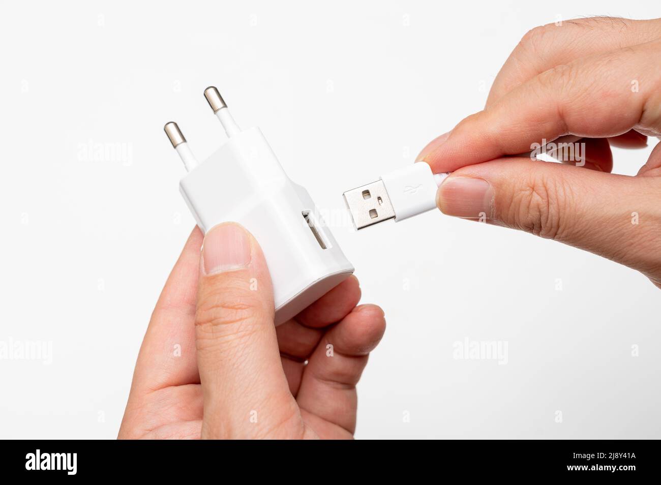 Male hand connecting USB cable to charging adapter. Stock Photo