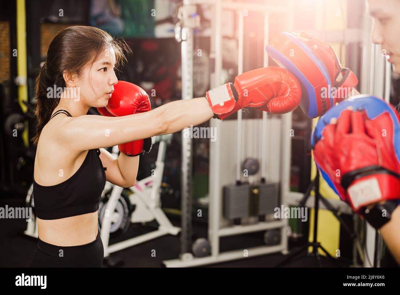 Asian female boxer training Punch the trainer's aim. Stock Photo