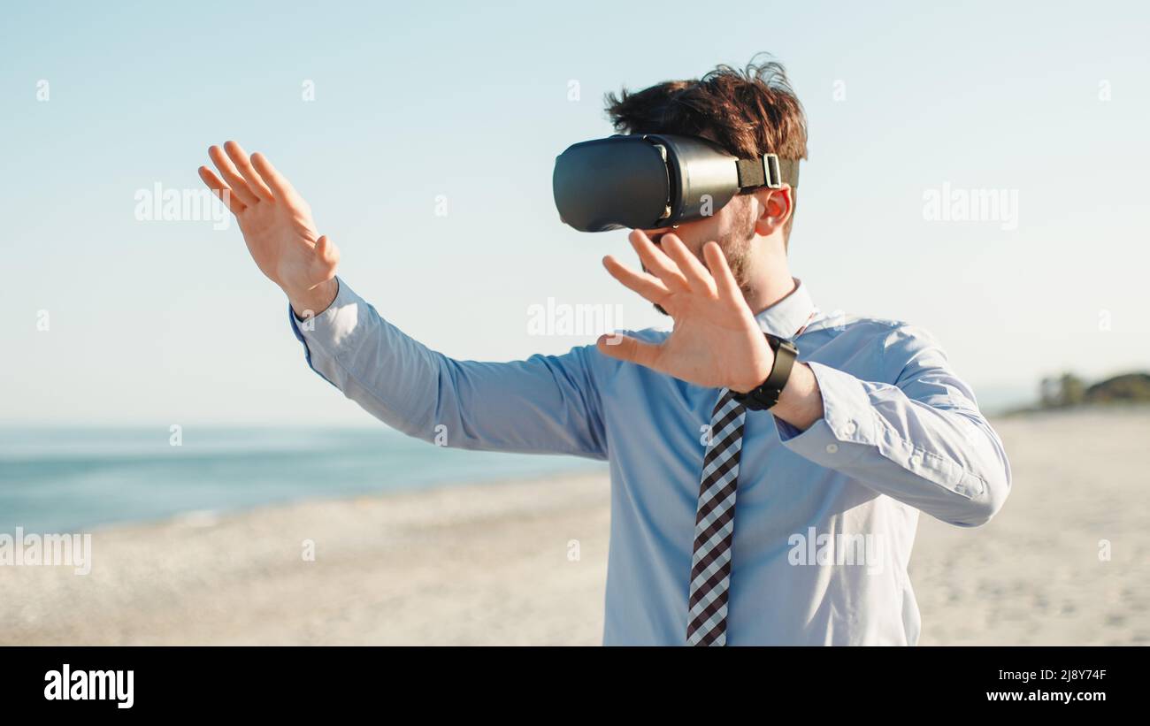 businessman with augmented reality viewer in metaverse beach Stock Photo