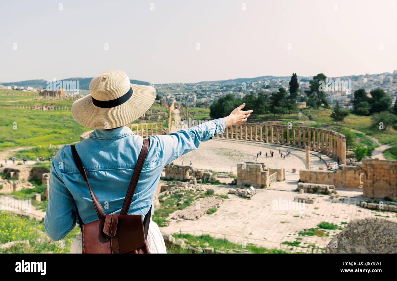 young woman tourist in color dress and hat enjoying the Oval Forum in ancient Roman city Gerasa, present-day Jerash, Jordan Stock Photo