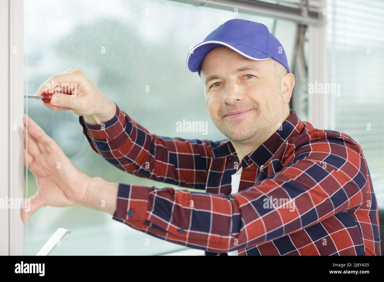 worker fasten the handle to a plastic window Stock Photo