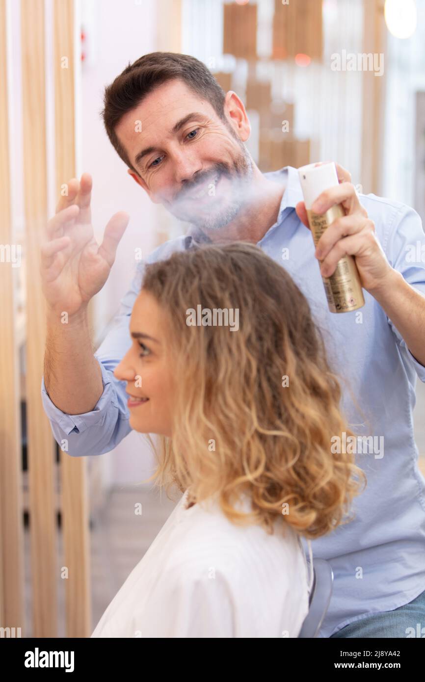 male hairdresser spraying finished style Stock Photo