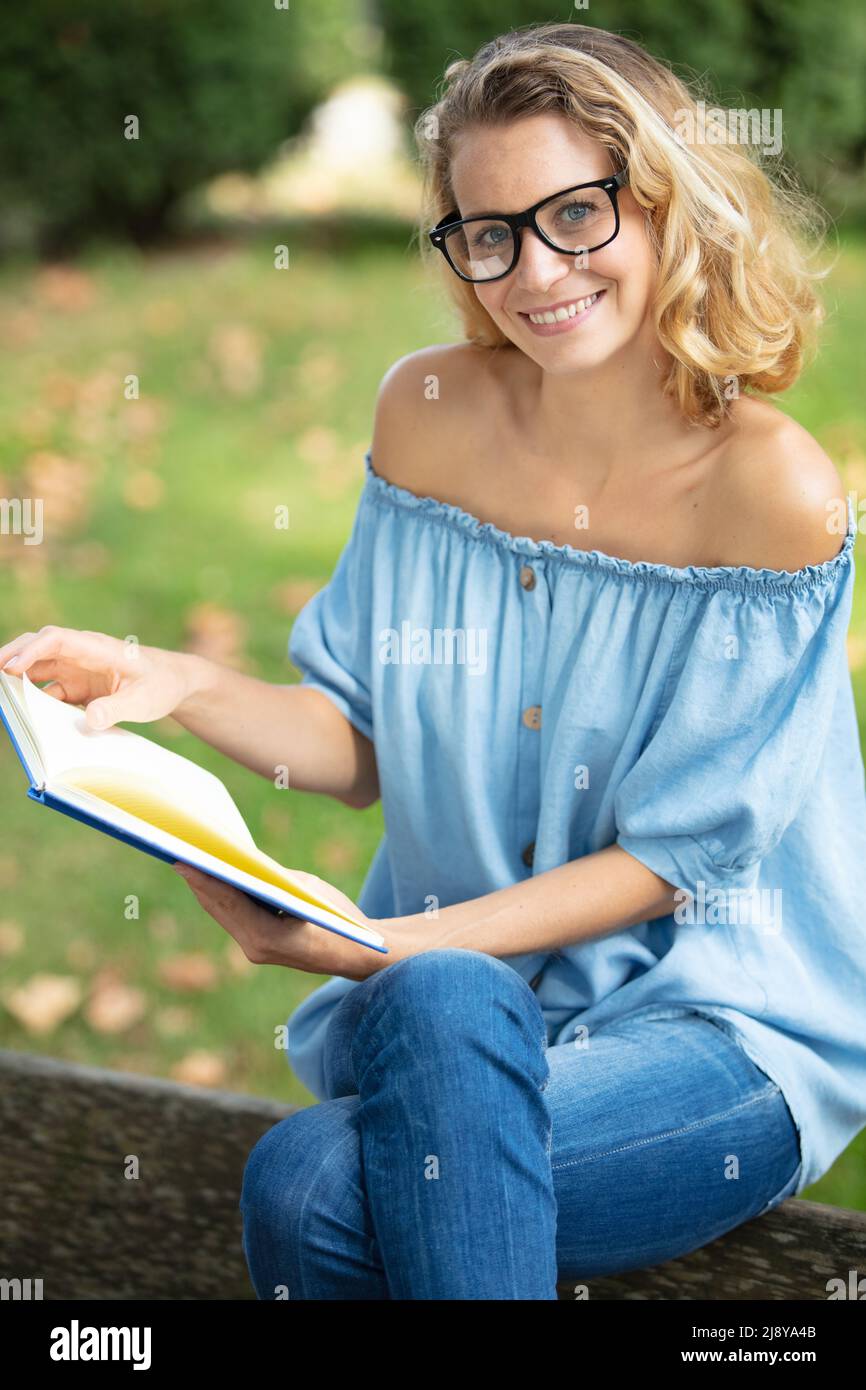 happy woman with boook sitting on a park bench Stock Photo - Alamy