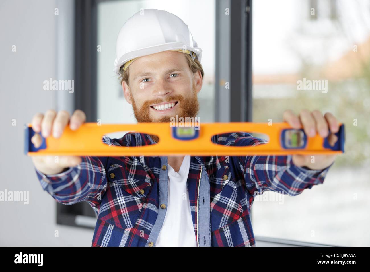 smiling builder in a hardhat using a spirit level Stock Photo
