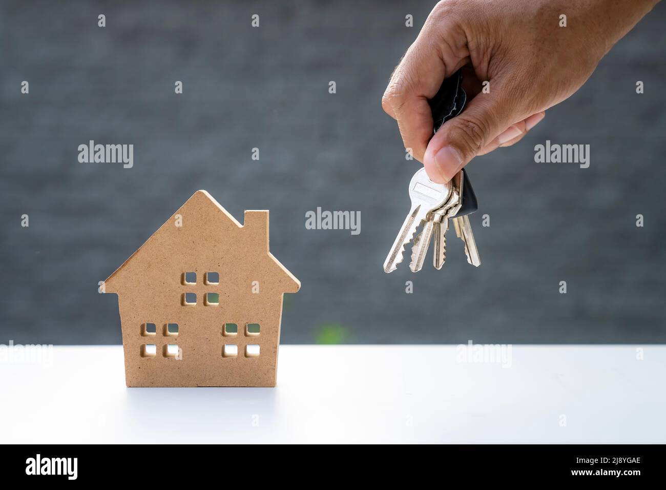 hand holding keys and wooden house model, house sales agent Stock Photo ...