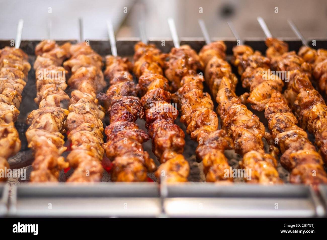 Chicken kebabs cooking on a charcoal grill at Christmas market Hyde Park Winter Wonderland in London Stock Photo
