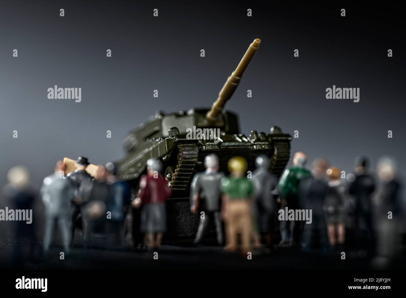 Figures with the model of a tank in the background as a symbol of rearmament Stock Photo