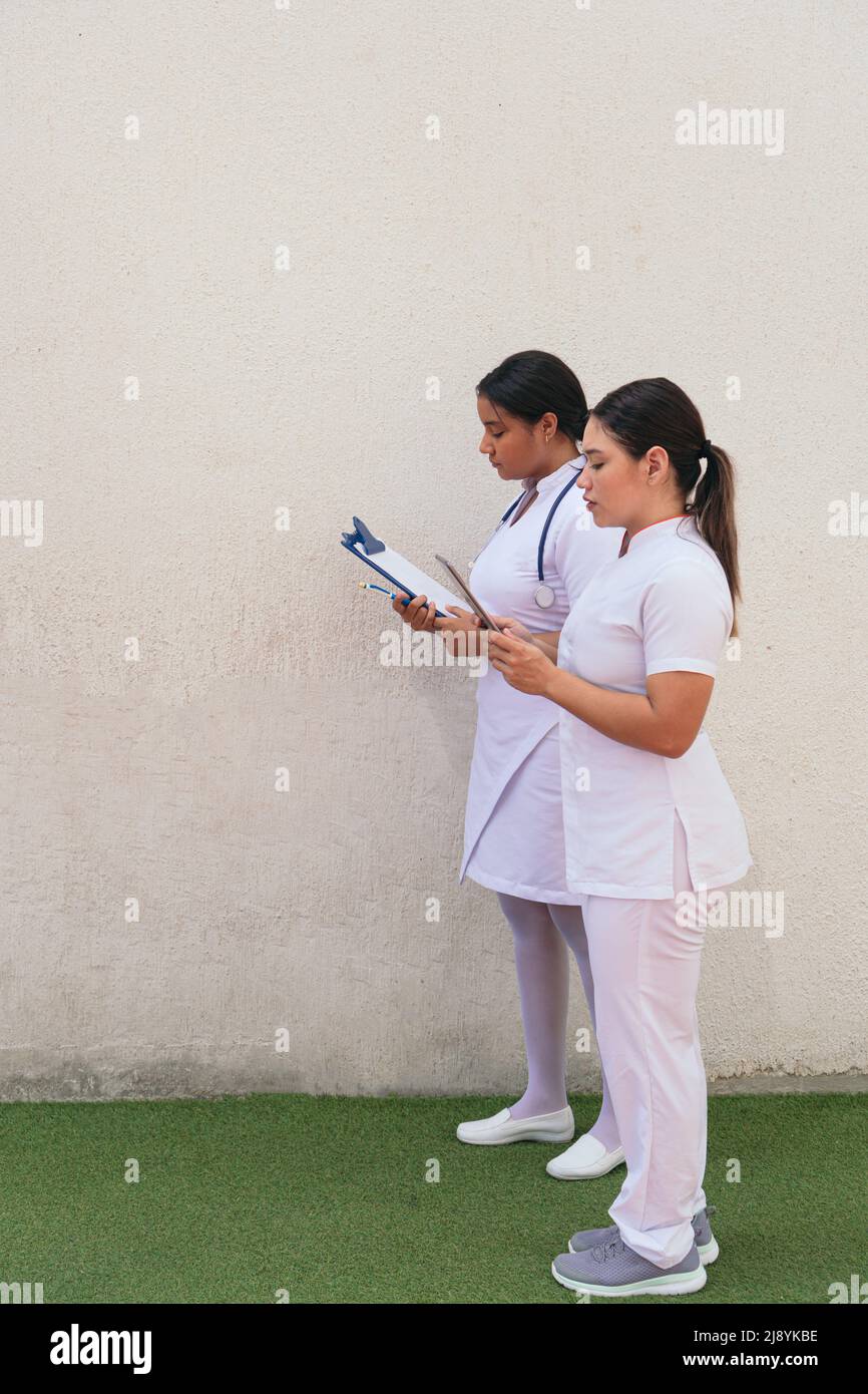Latin Female nurses using digital tablet in hospital corridor Stock Photo
