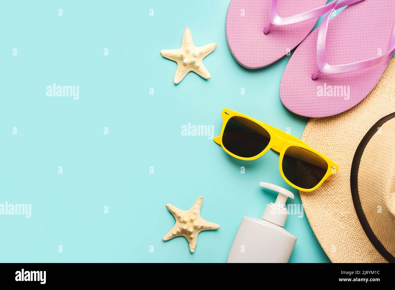 Summer holiday concept.Top view of flip flops,sunglasses,sunscreen,starsfish and hat with space for text for text over blue background Stock Photo