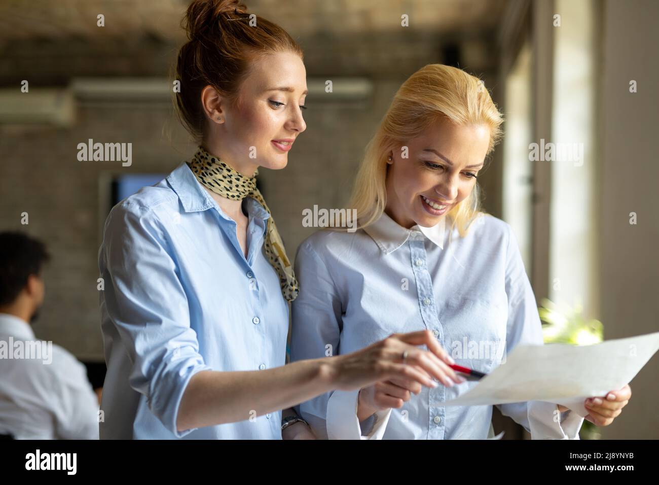 Portrait of two young business people talking about documents in office Stock Photo