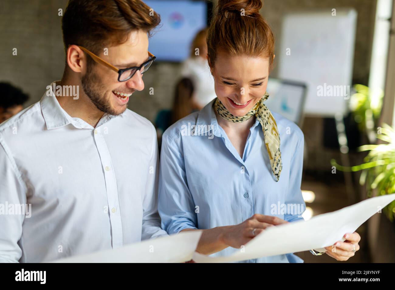 Portrait of two young business people talking about documents in office Stock Photo