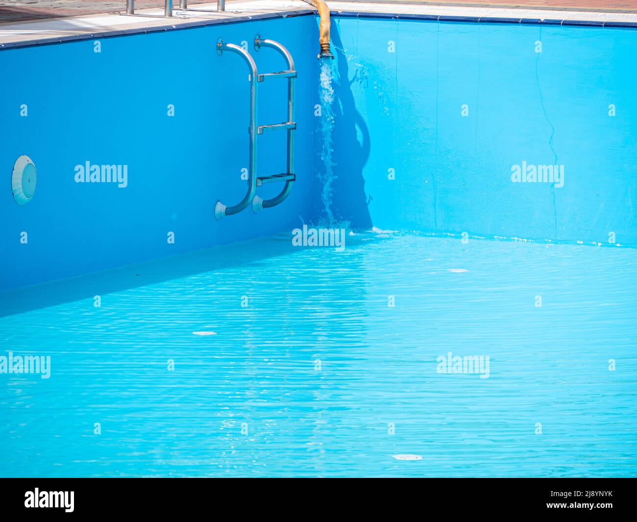 Pouring fresh water into swimming pool. Clear blue water refreshing ...