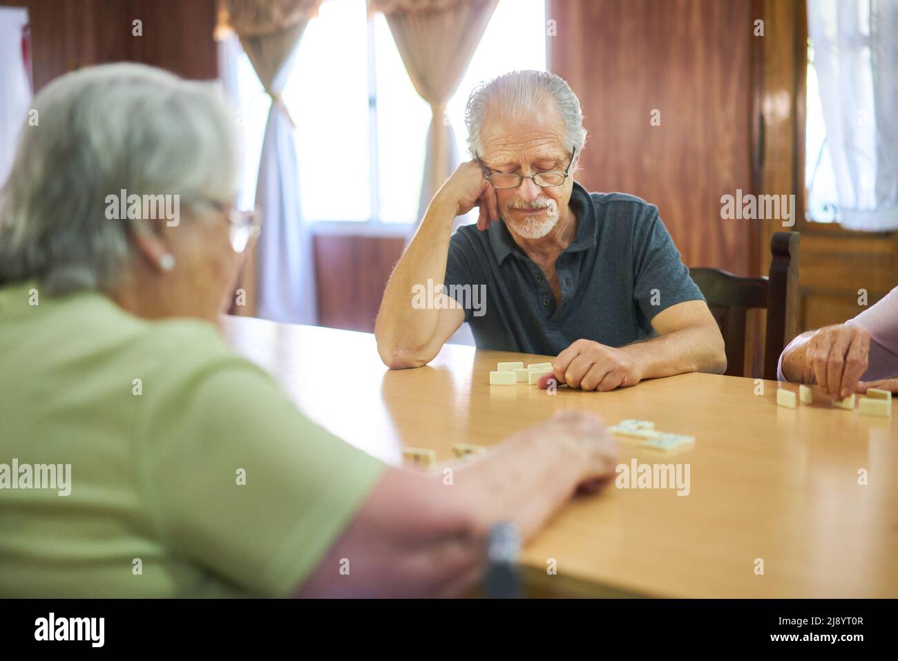 Senior with dementia concentrating while playing dominoes with friends