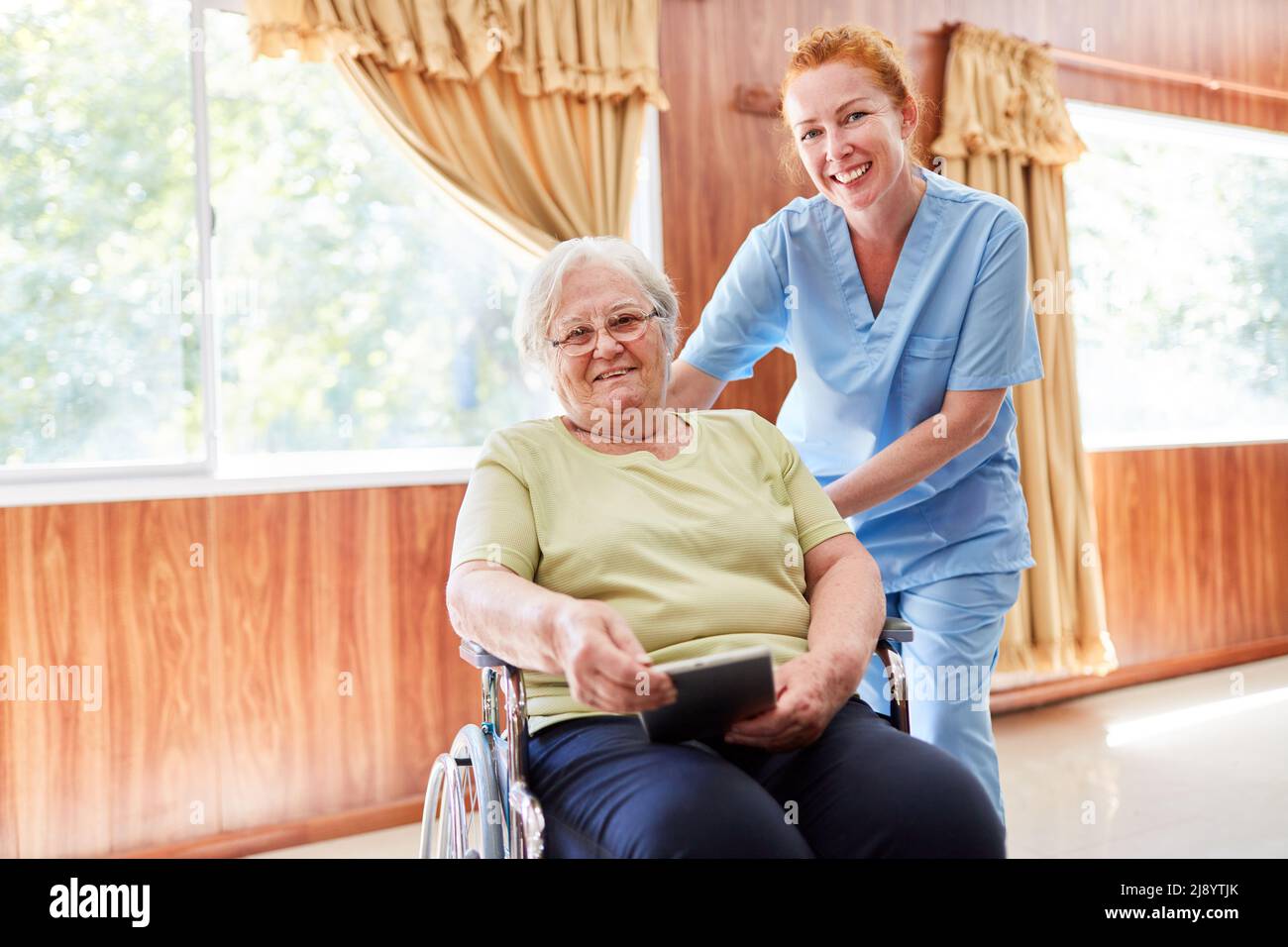 Happy elderly woman in a wheelchair being cared for by a nurse after a