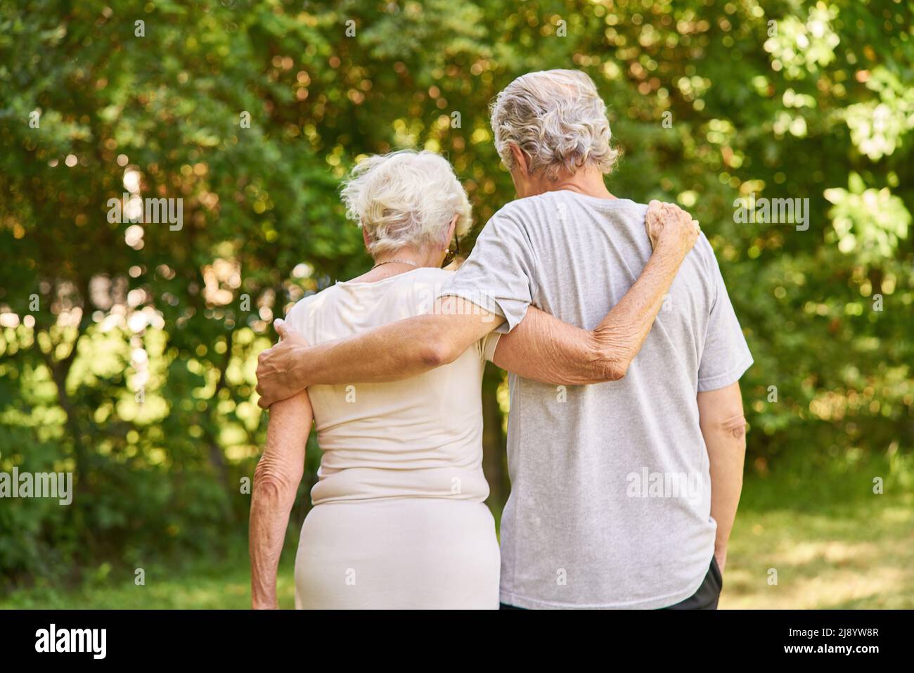 Happy senior couple walking arm in arm in nature in summer Stock Photo