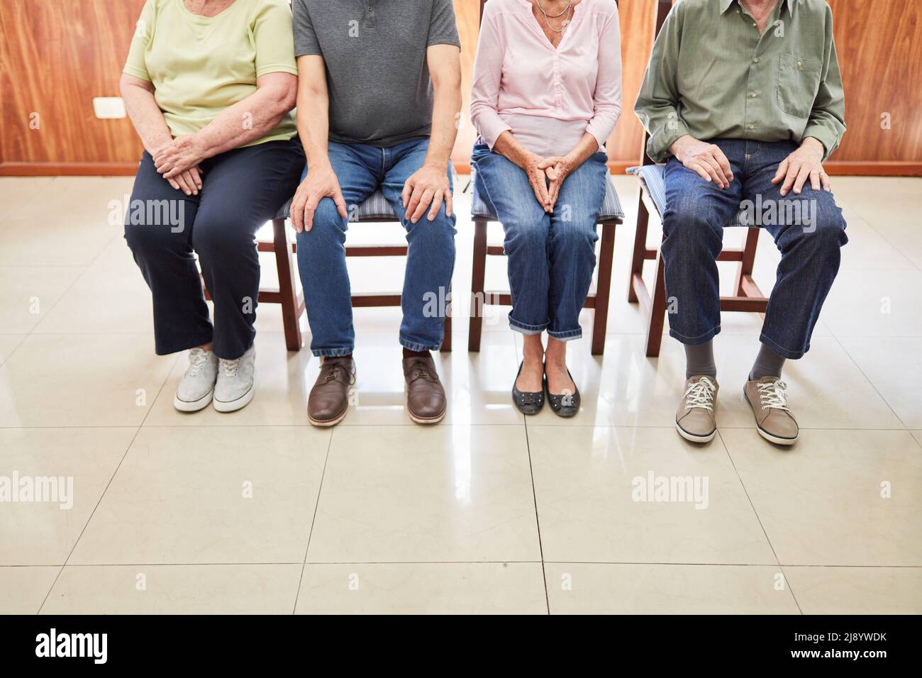 Group of seniors sitting on chairs in waiting room as concept of