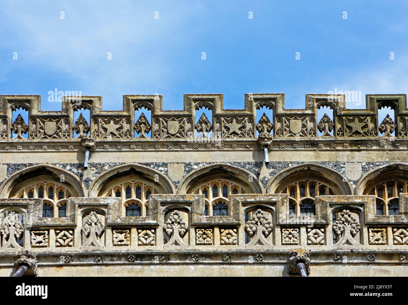 A view of the detailed carved stonework on the clerestory and open battlements at the parish Church of St Peter and St Paul at Lavenhan, Suffolk, UK. Stock Photo