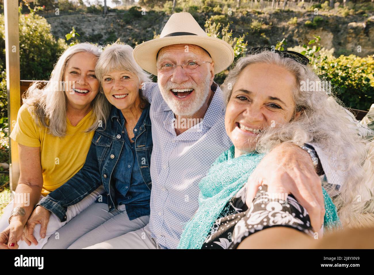 Excited senior friends taking a selfie together during vacation. Cheerful elderly people enjoying a weekend getaway at a spa resort. Group of happy se Stock Photo