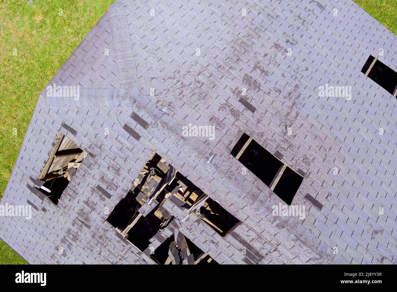Damaged tiled roofing with broken tiles and a hole on the roof Stock Photo