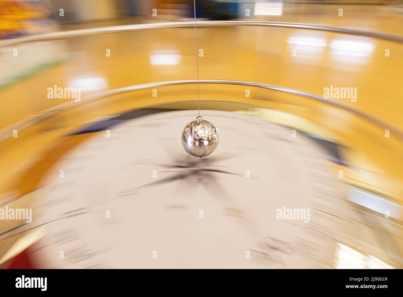 Photographic sweep of a foucault pendulum along its path through a compass rose Stock Photo