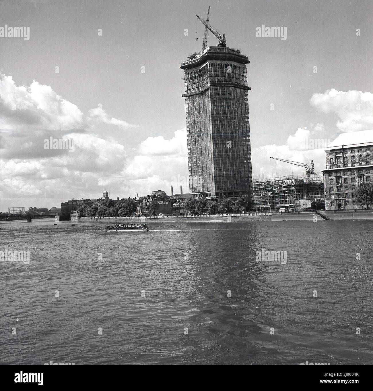 1962, historical, view from the river Thames of a new high-rise office building under construction on the South Bank of the river, London, England, UK. Built by John Mowlem & Co for the British engineering company, Vickers and originally known as Vickers House or Tower, it later became known as Millbank Tower.  Construction on this modern skyscraper started in 1959 and on completion in 1963, it became the tallest building in the UK at 387ft. In the 1990s, the building became famous as the headquarters of the Labour Party. It was Grade II listed in 1995. Stock Photo