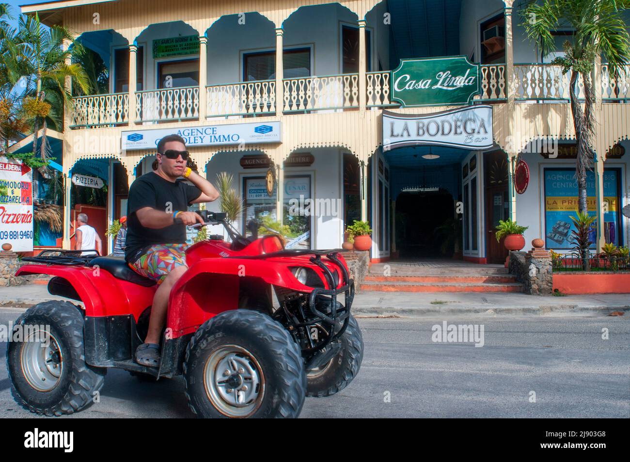 Local man in a ATV All terrein vehicle quad in Las Terrenas city center Samana, Dominican Republic, Carribean, America.   Las Terrenas is the perfect Stock Photo