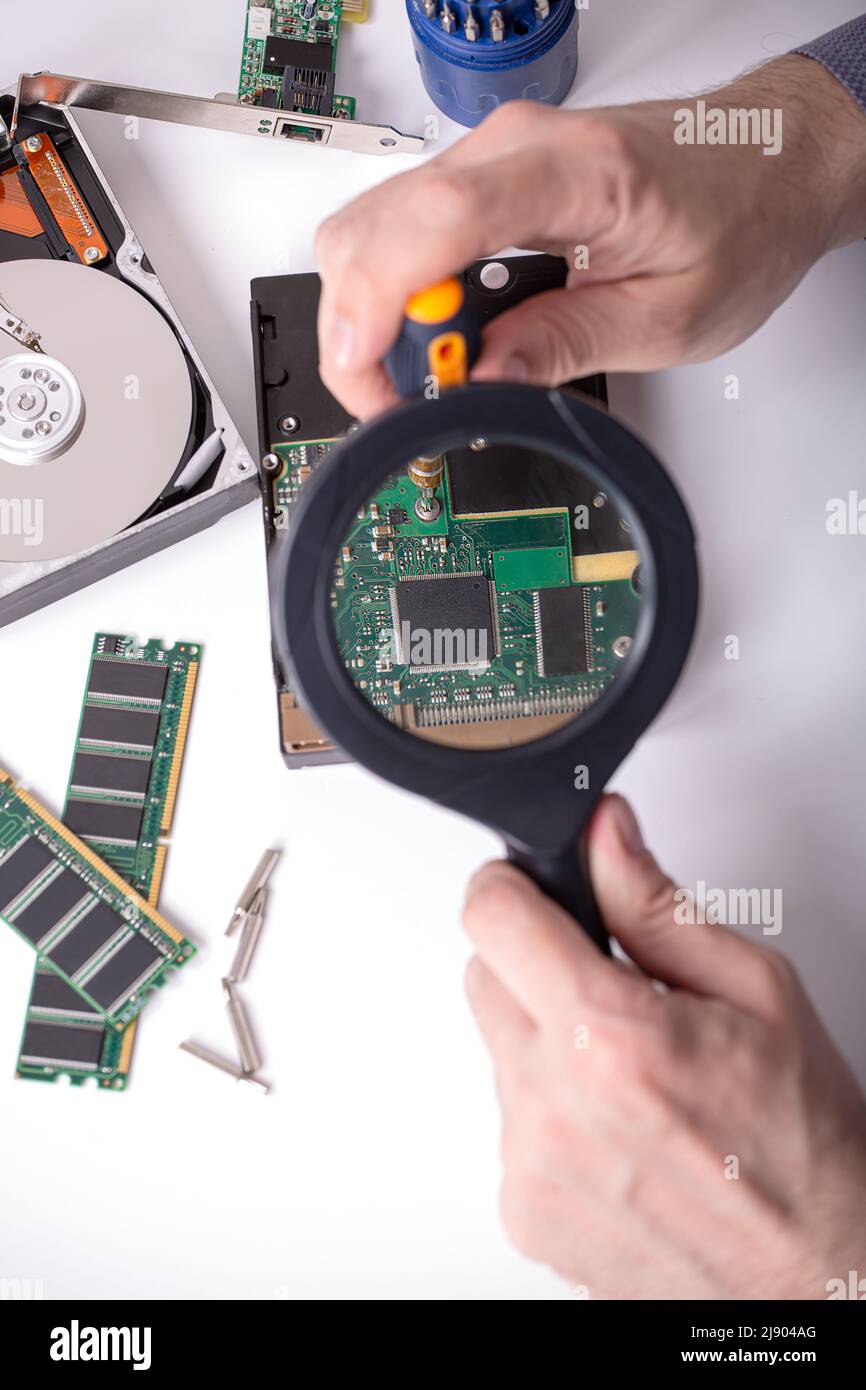 The master examines the disassembled hard drive through a magnifying ...