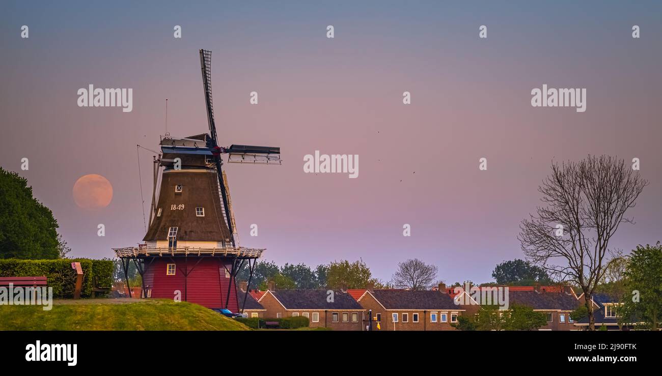 Sunset and moonrise with a full moon near Flour Mill 'De Hoop' in the Dutch town of Dokkum, in the province of Friesland in the northern part of the N Stock Photo