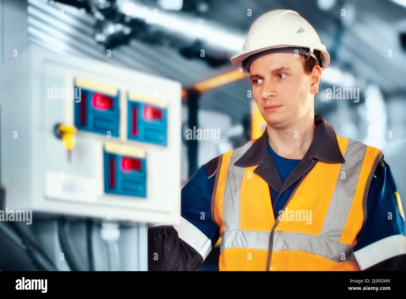 Industrial engineer in helmet inspects or adjusts equipment at gas processing plant or plant. Authentic scene workflow. Stock Photo