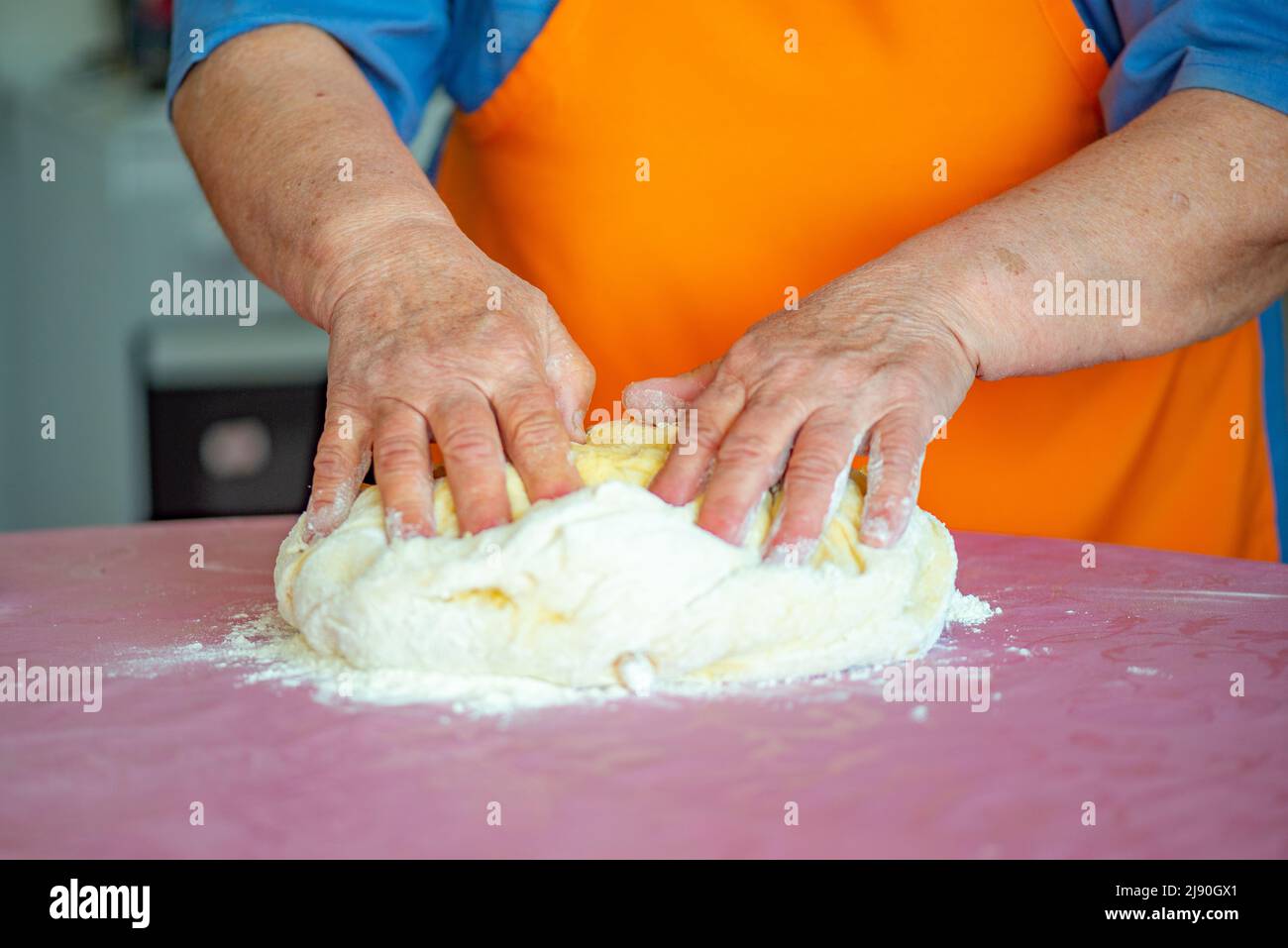 grandmother kneads dough for Easter cakes on the table Stock Photo