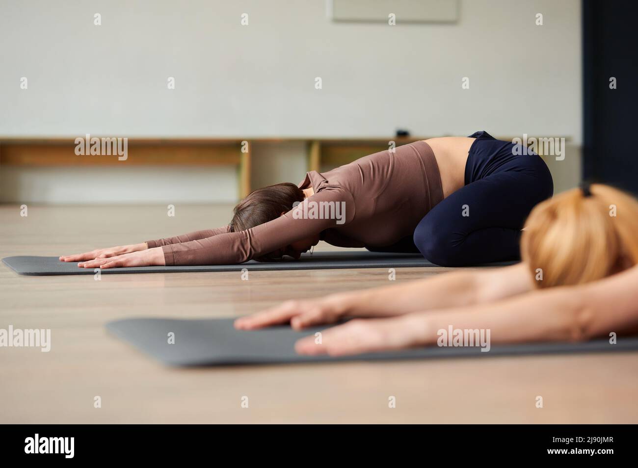 Group of women does muscle stretching in the gym on yoga mats, a
