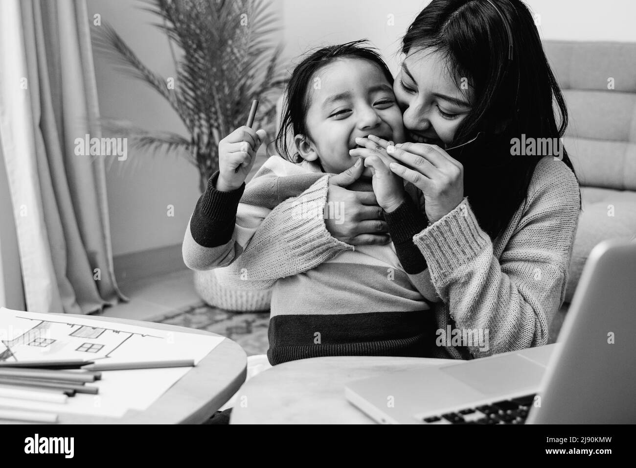 Happy Latin American mother and son hugging each other at home - Family love concept - Black and white editing Stock Photo