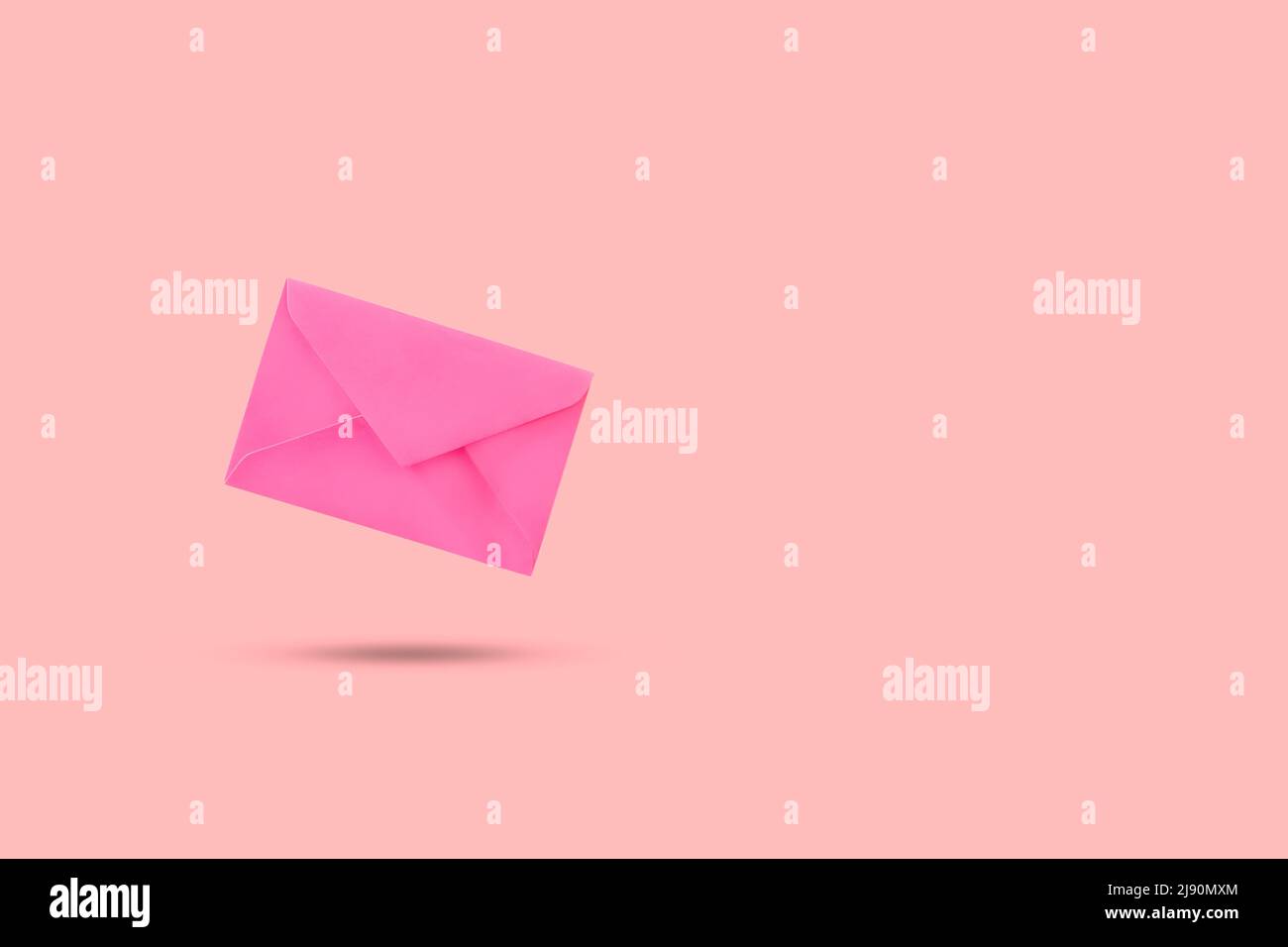 A pink envelope floating on a pink background with copy space Stock Photo