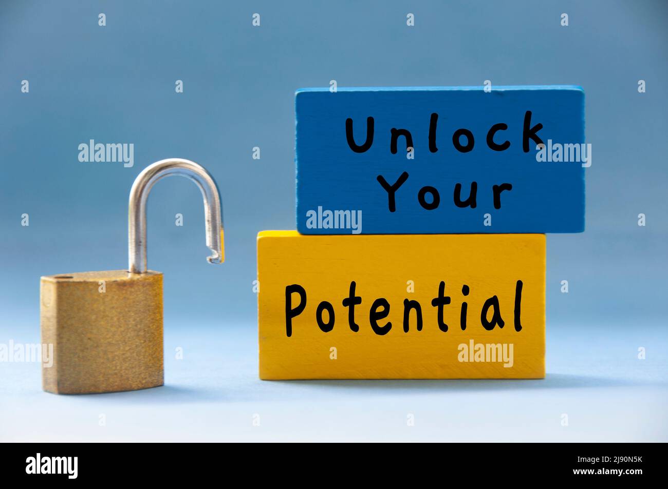 Unlock your potential text on wooden blocks with pad lock on light blue background. Motivational concept Stock Photo