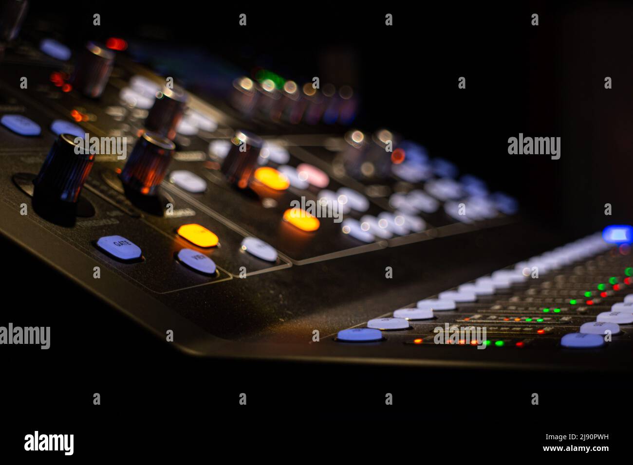 close-up ambient shoot of a modern digital audio mixing device for professional sound mixing at a concert venue in dim partial lighting with selective Stock Photo