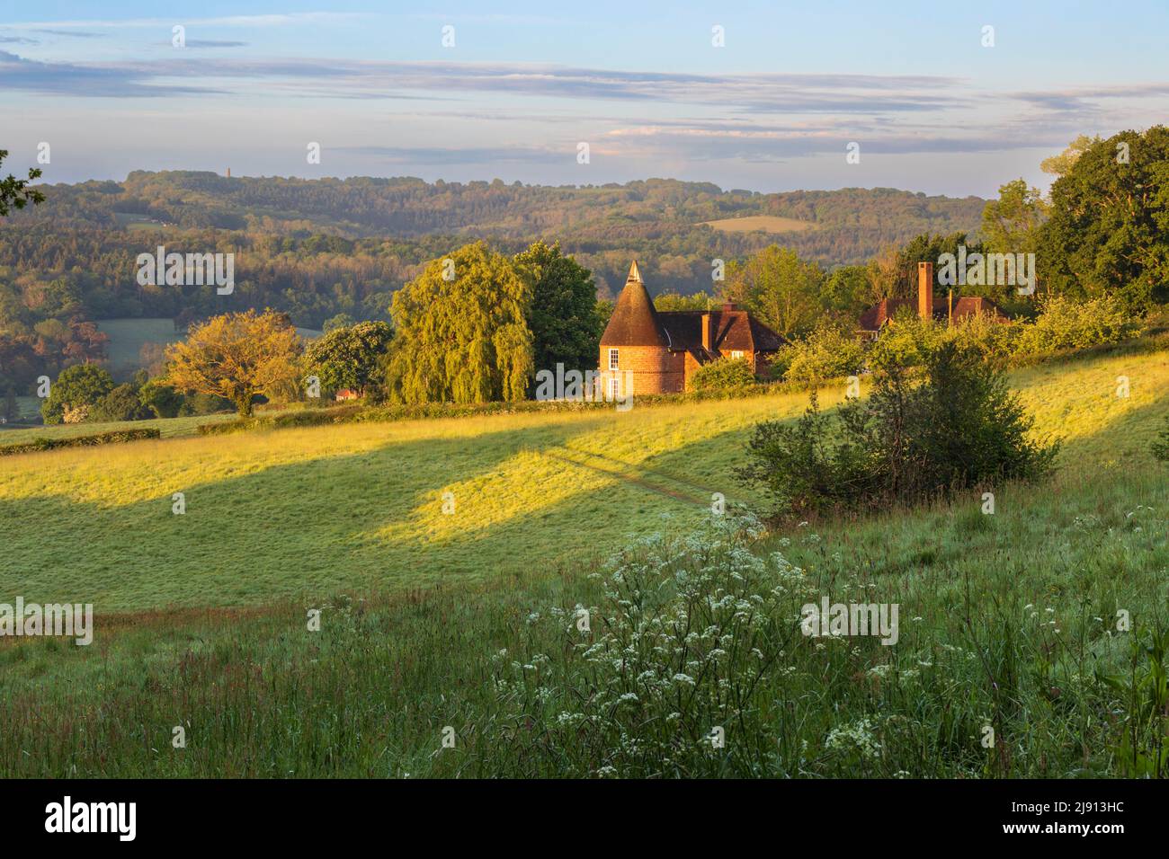 Former oast house in morning sunlight set in High Weald landscape viewed from public footpath, Burwash, East Sussex, England, United Kingdom, Europe Stock Photo