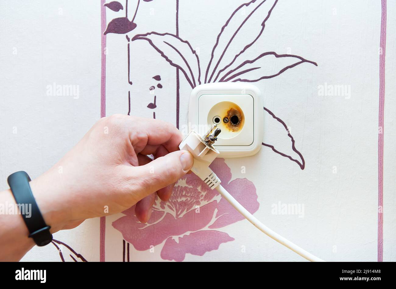 The plug and socket are burnt, the man is holding the burnt socket