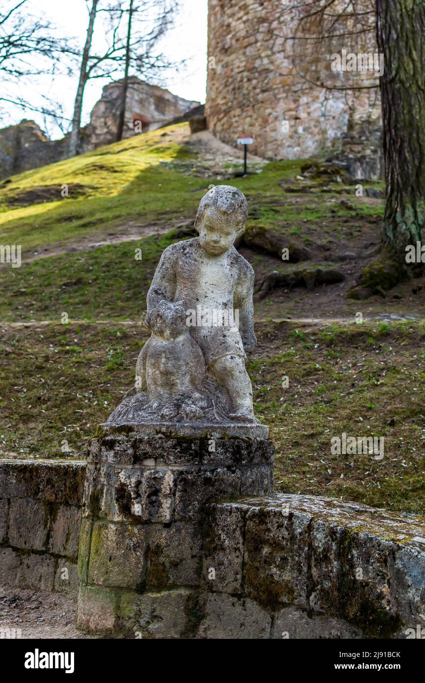 Travertine sculpture - a figure of a child with owl at the step’s edge in the Cesis Castle Park's hill, Latvia. Stock Photo