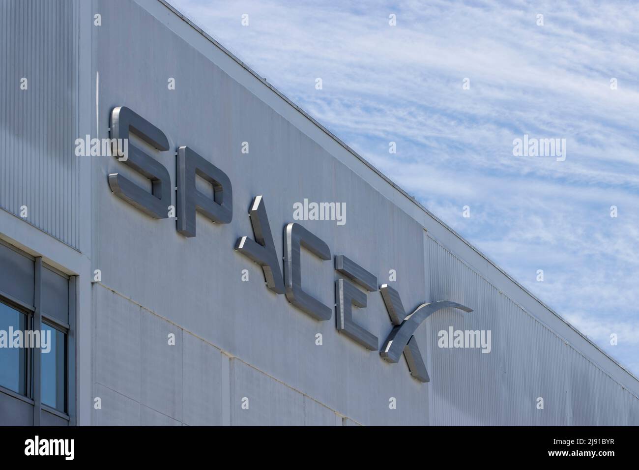 Closeup of SpaceX logo seen at its headquarters in Hawthorne, California, against a dramatic sky, seen on May 10, 2022. Stock Photo