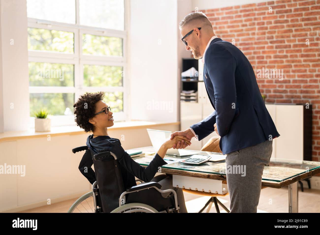 Two Happy Businesspeople In Office Shaking Hands Stock Photo