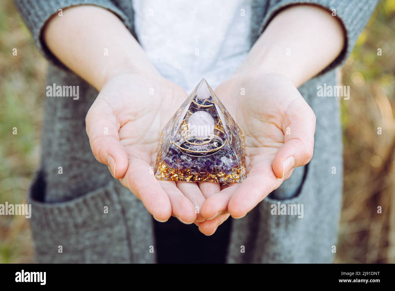 Close up view of woman hands holding and using Orgonite or Orgone pyramid. Converting negative energy to positive energy and have healing powers. Stock Photo
