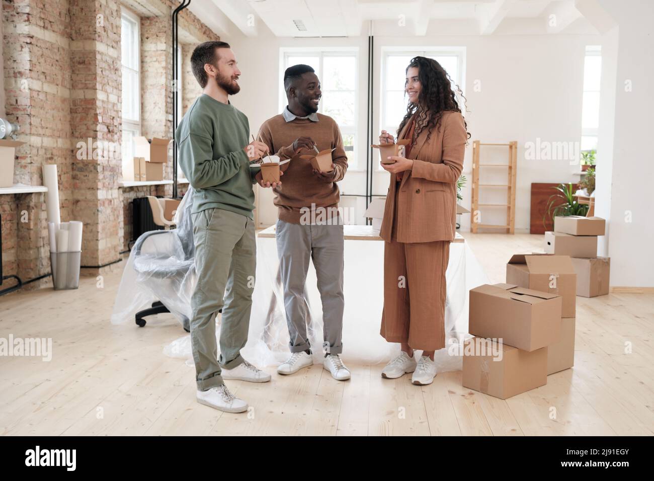 Group of smiling young multi-ethnic colleagues standing in new office with  moving boxes and eating Chinese food while communicating together Stock  Photo - Alamy