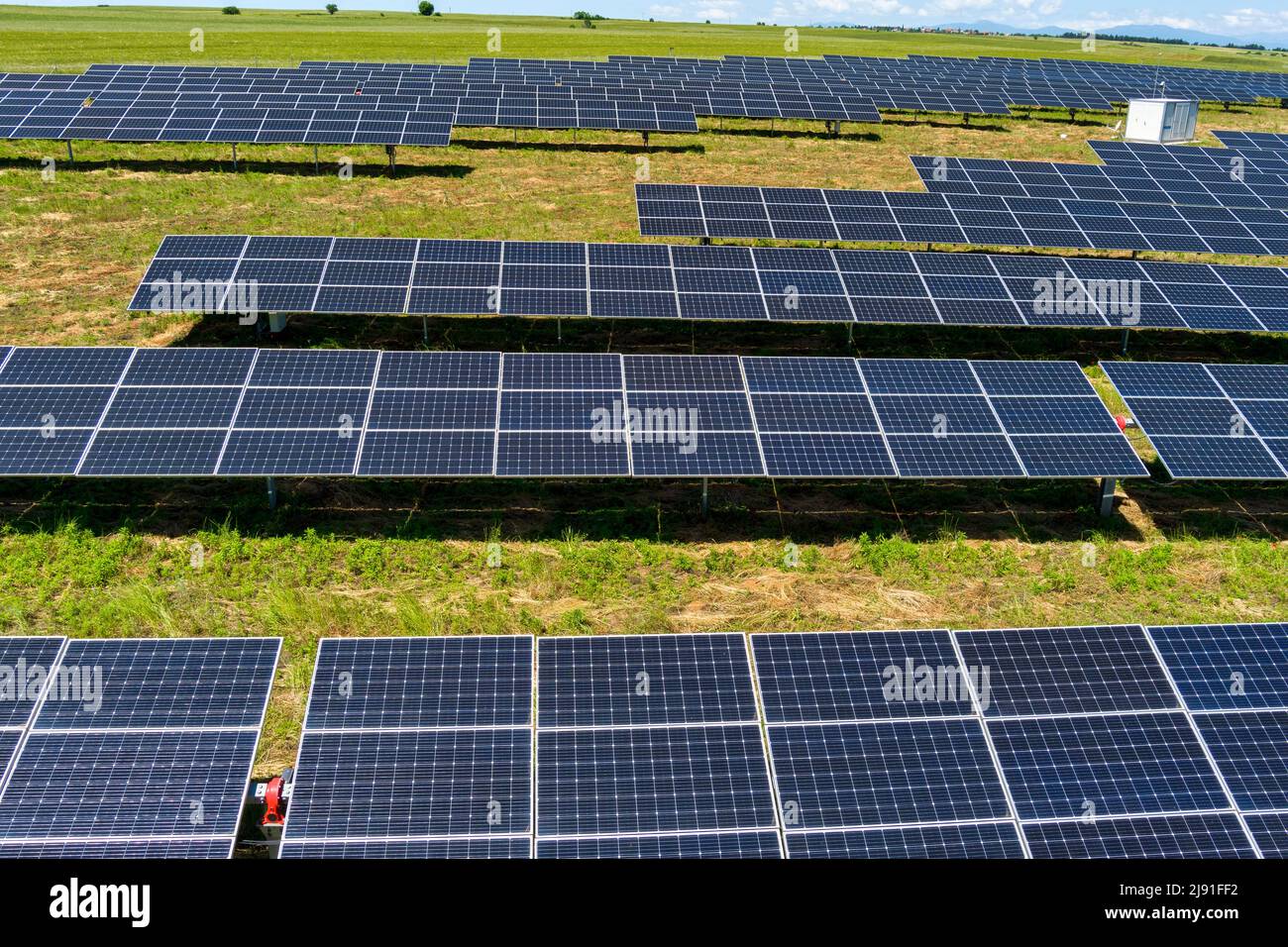 Aerial view photovoltaic panels park on green field in north Greece. Blue sky reflecting in solar panels rows. Futuristic alternative power station. S Stock Photo