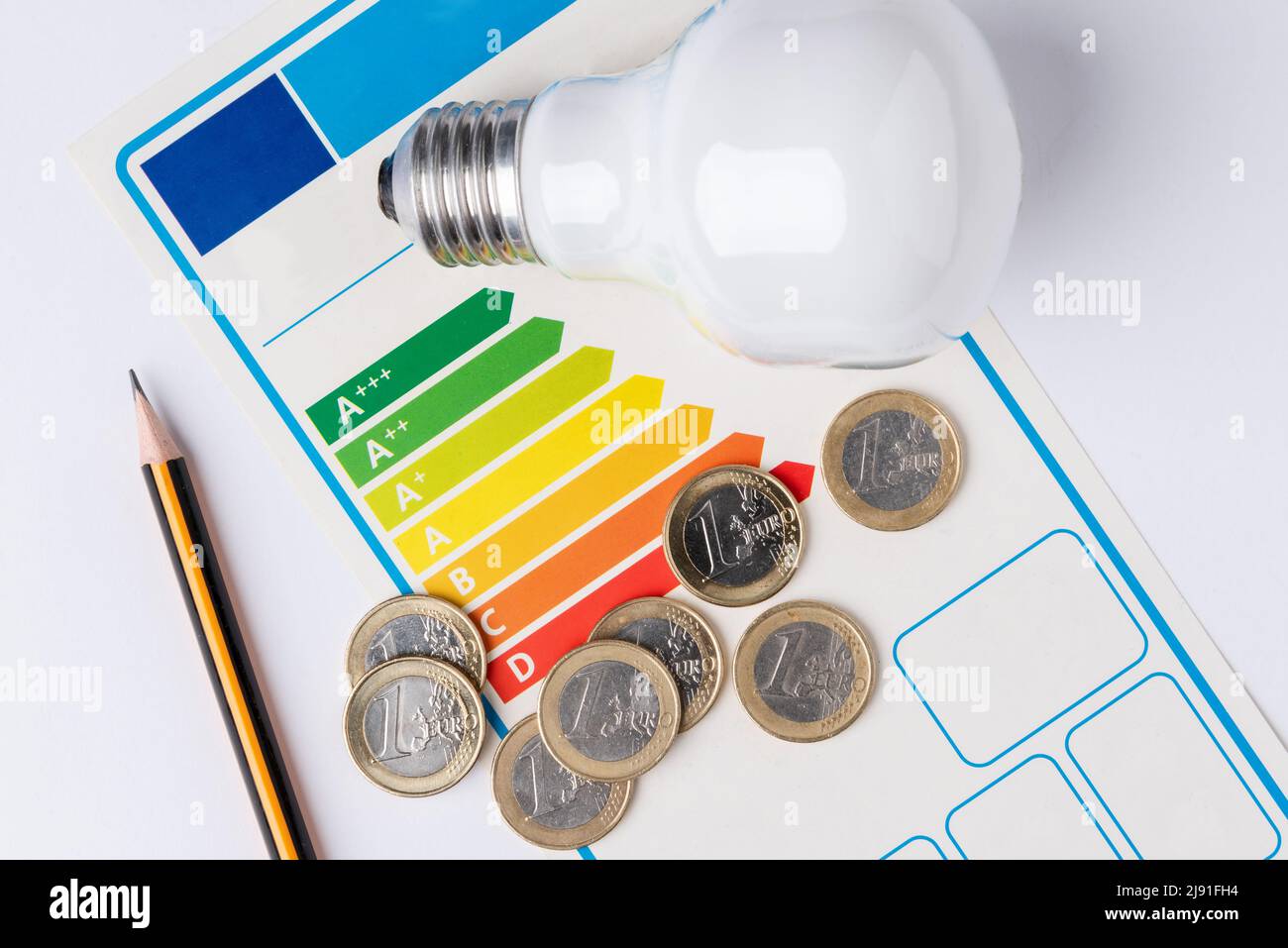 Energy efficiency scale with a light bulb, a pencil to make calculations and coins representing the cost of energy Stock Photo