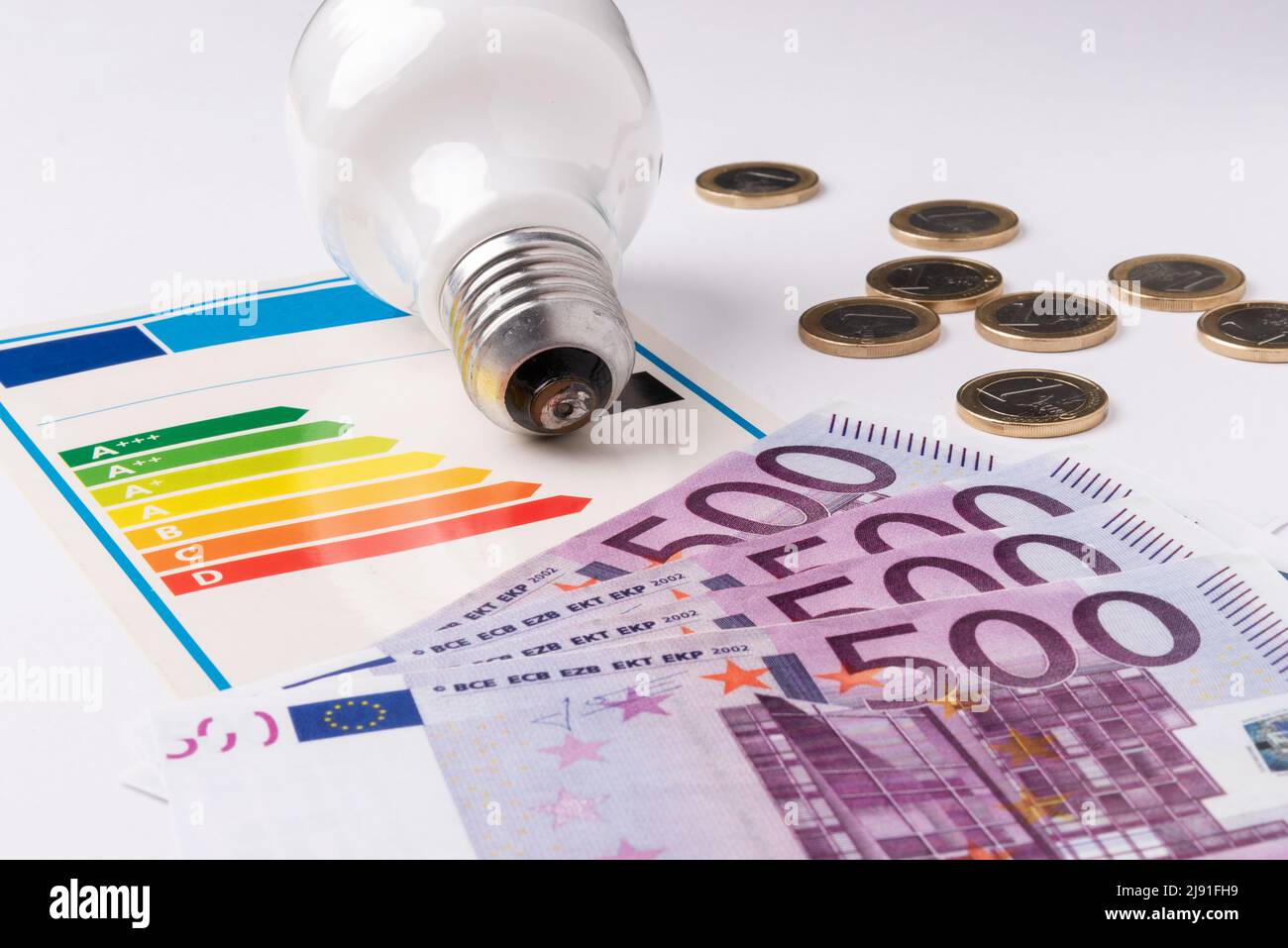 Energy efficiency scale next to a light bulb,   and banknotes representing the cost of energy Stock Photo