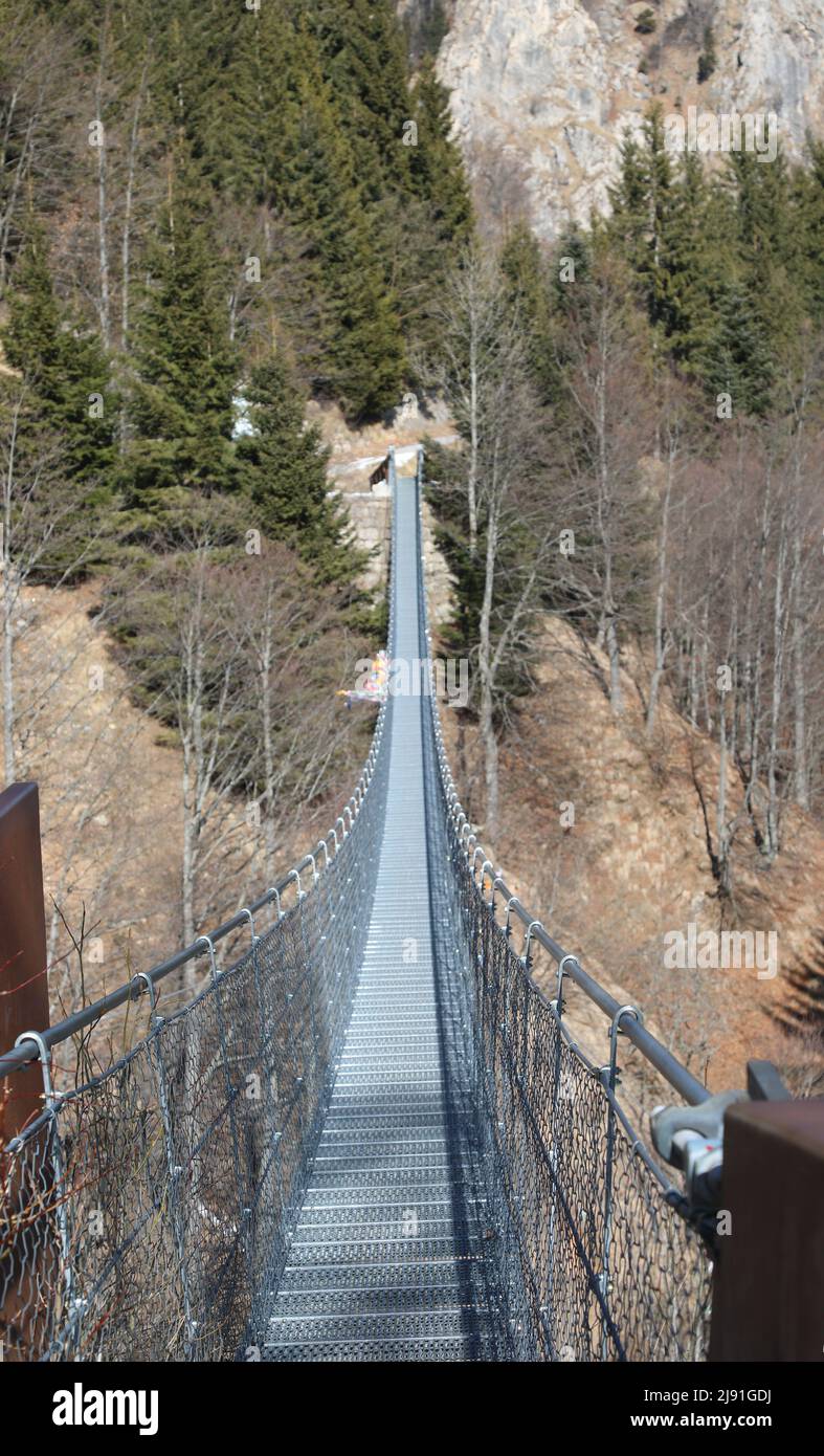 very long and spectacular suspension bridge made of steel ropes and metal sleepers to join the two ends of the mountain separated from the valley Stock Photo